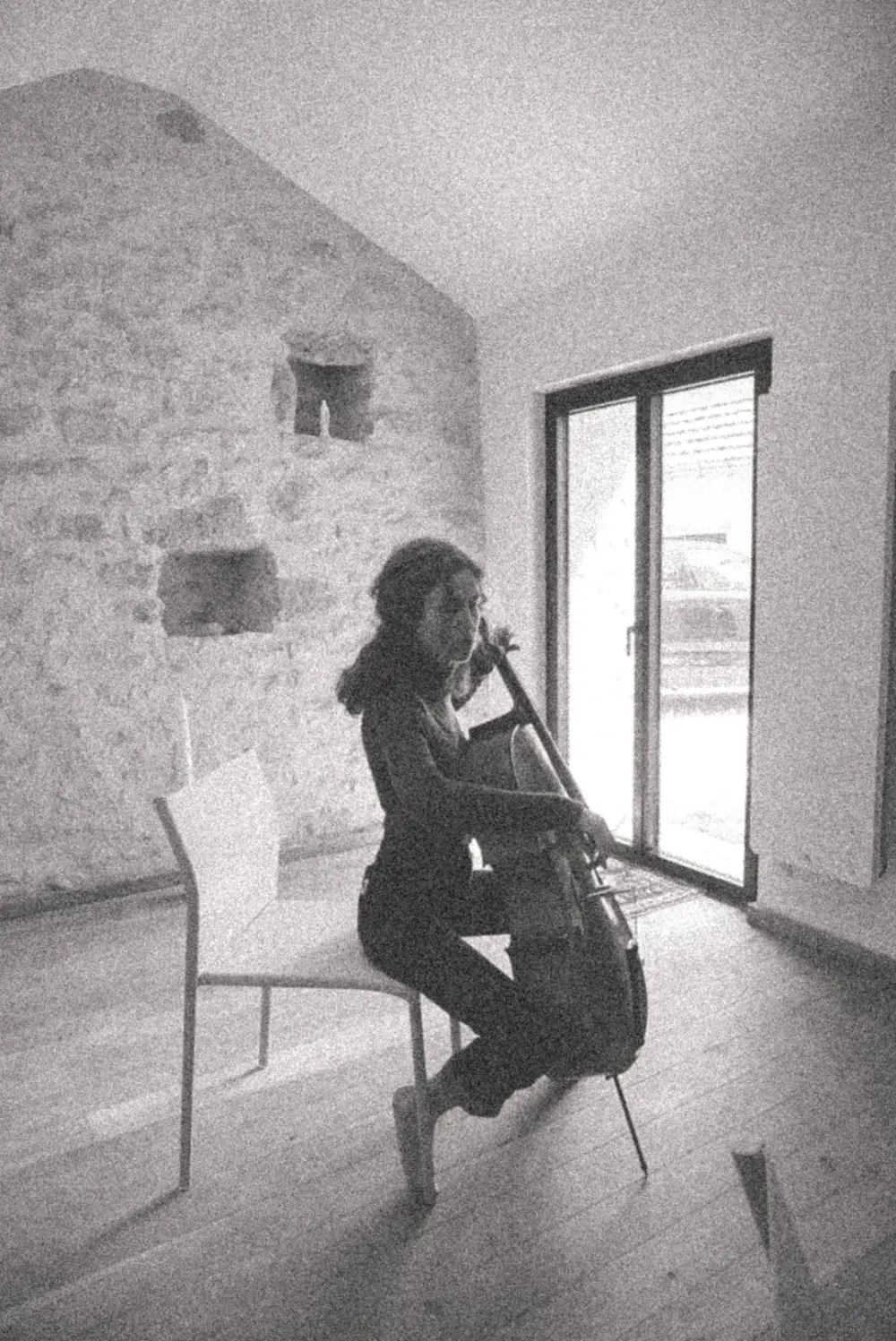 Eva Torres Soler joue du violoncelle dans le studio, devant un mur de pierre